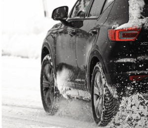 tight shot of tires on black Volvo driving in snow